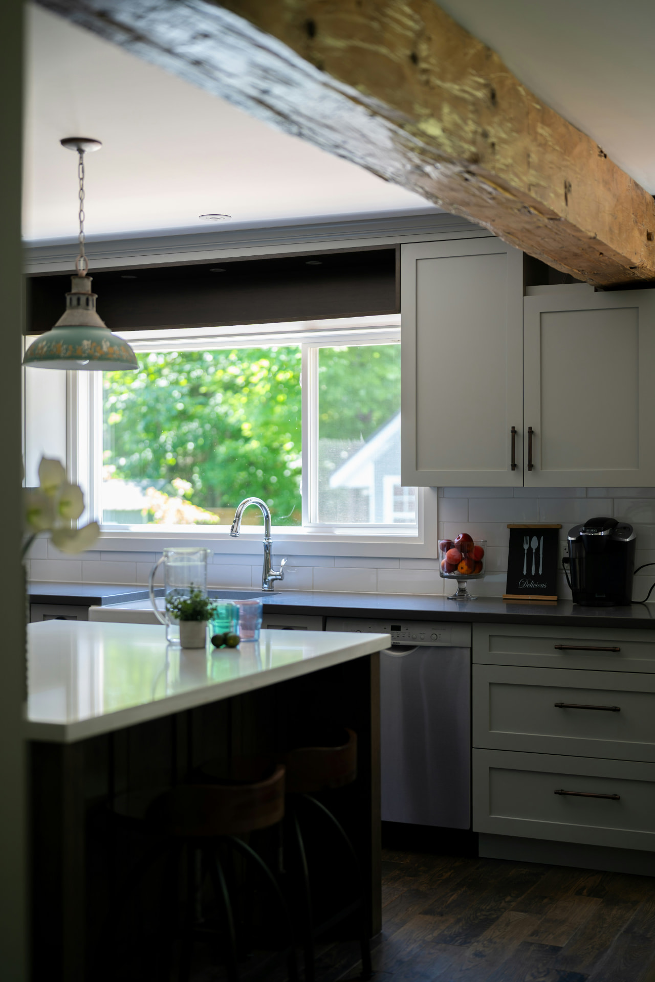 Bright refinished kitchen with painted shaker cabinets and a wood beam