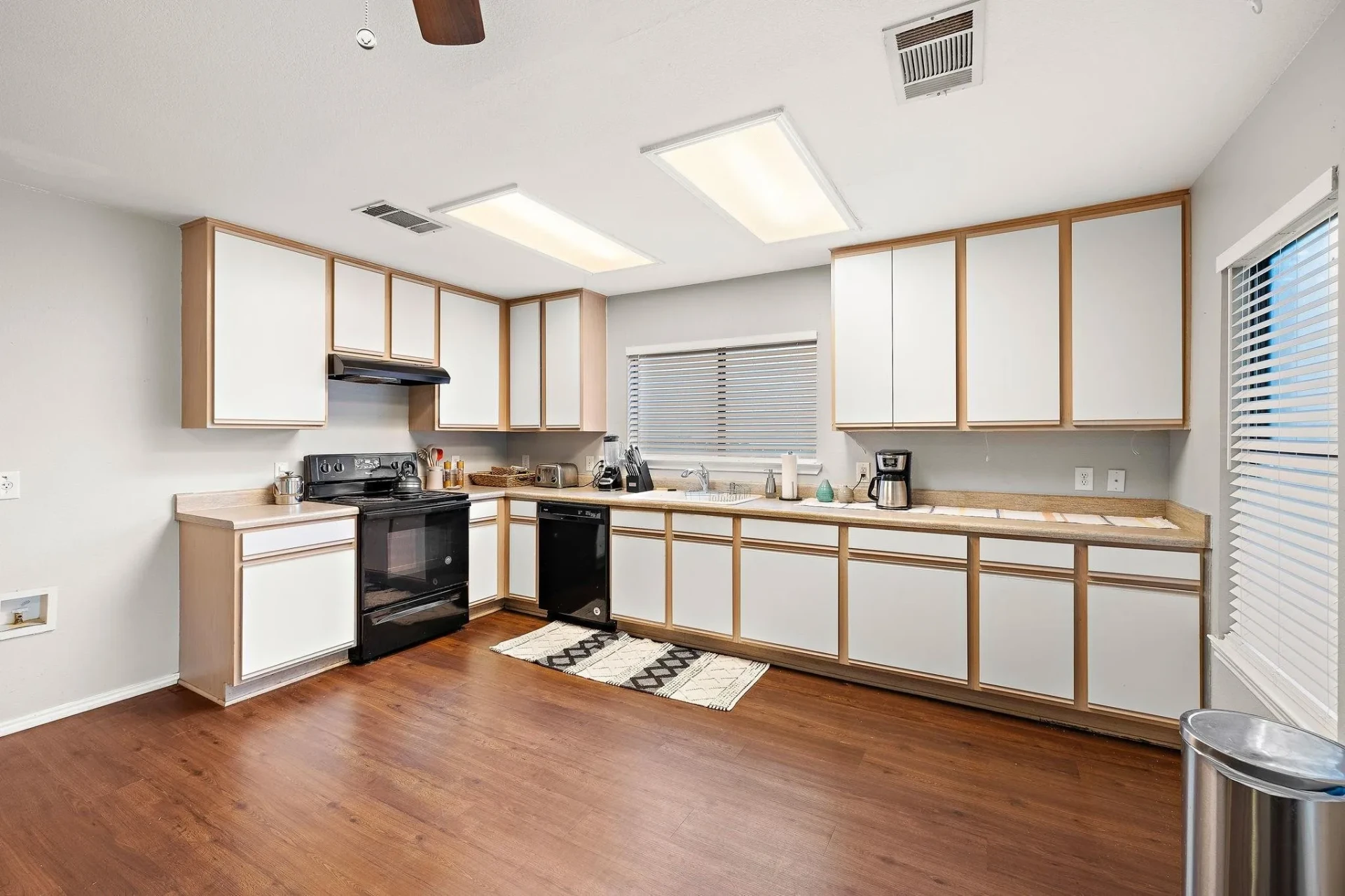 Dated kitchen with white and oak-trim cabinets, laminate countertops, and black appliances before remodeling in Round Rock