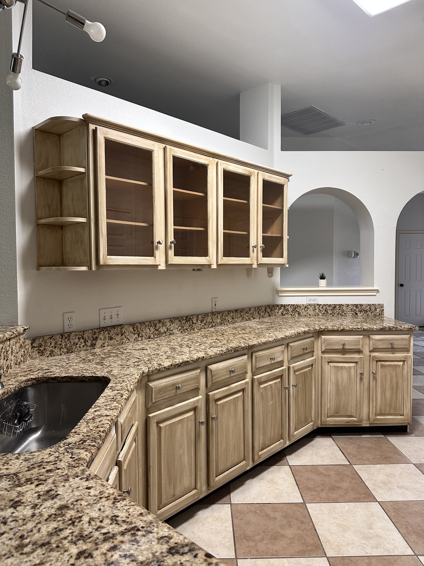 Worn beige stained kitchen cabinets with granite countertops before painting in Austin